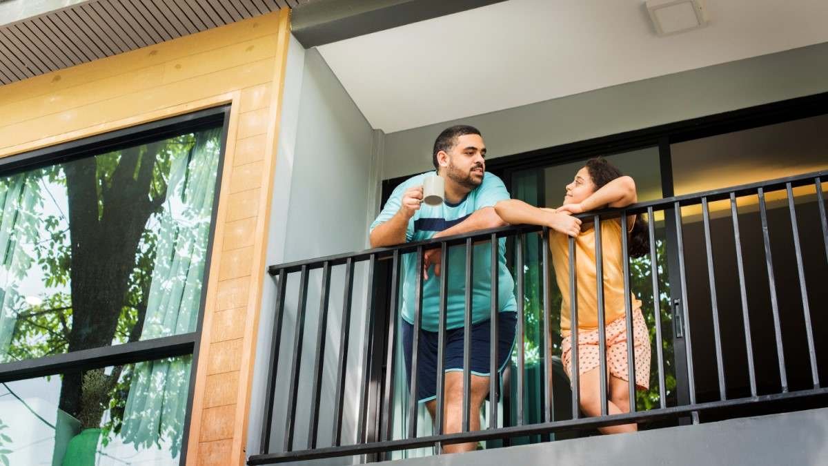 Homem e mulher conversando na varanda de seu apartamento.