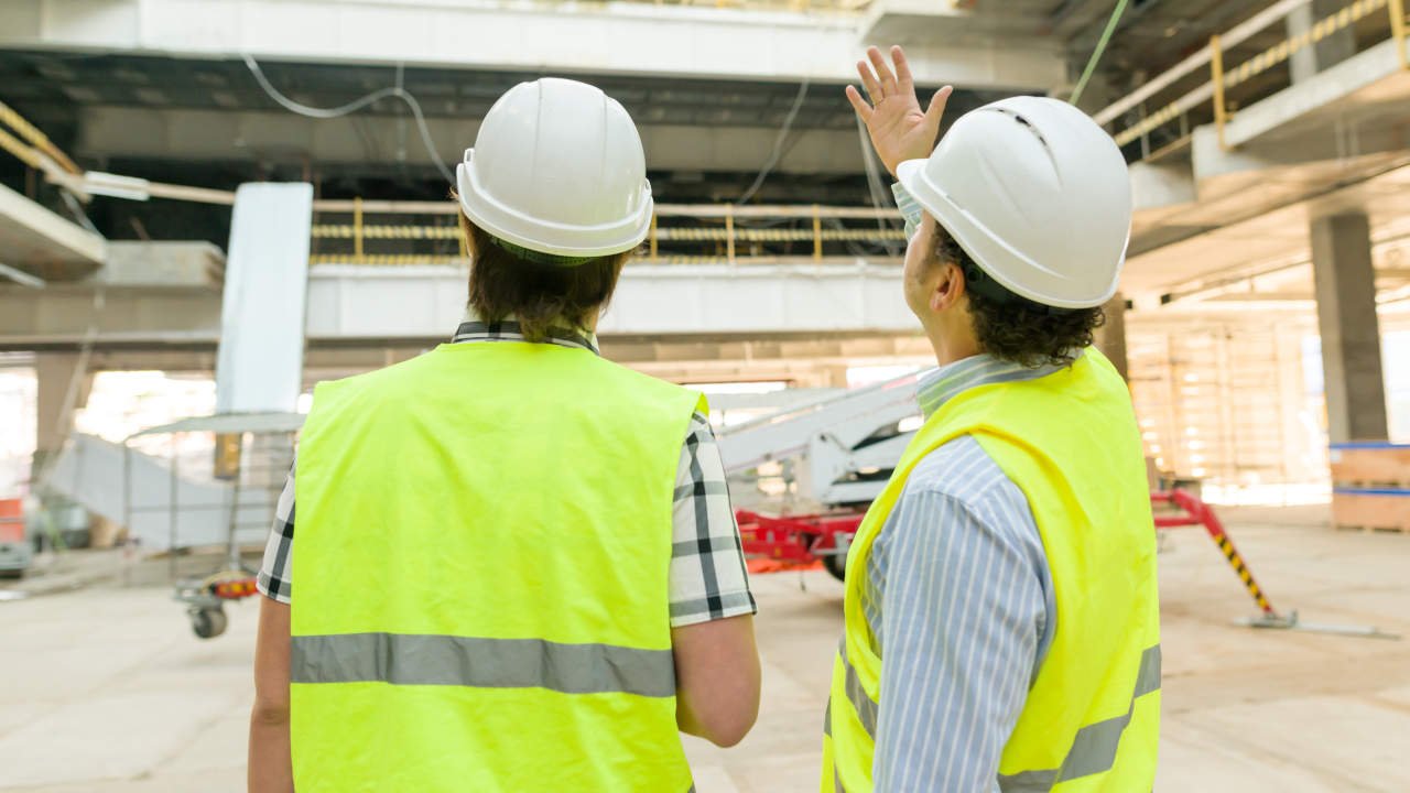 Engenheiros inspecionando uma obra com coletes de segurança em um canteiro de construção.