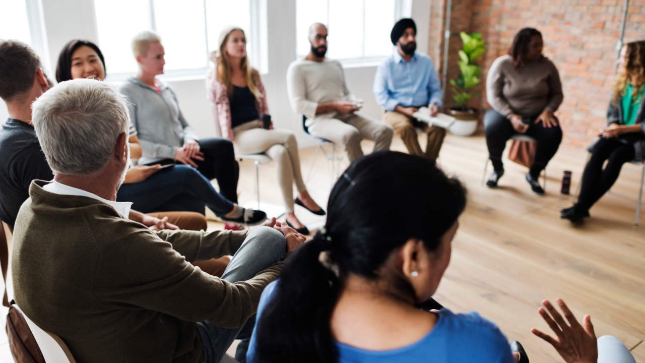 Pessoas sentadas em círculo participando de uma discussão em grupo.