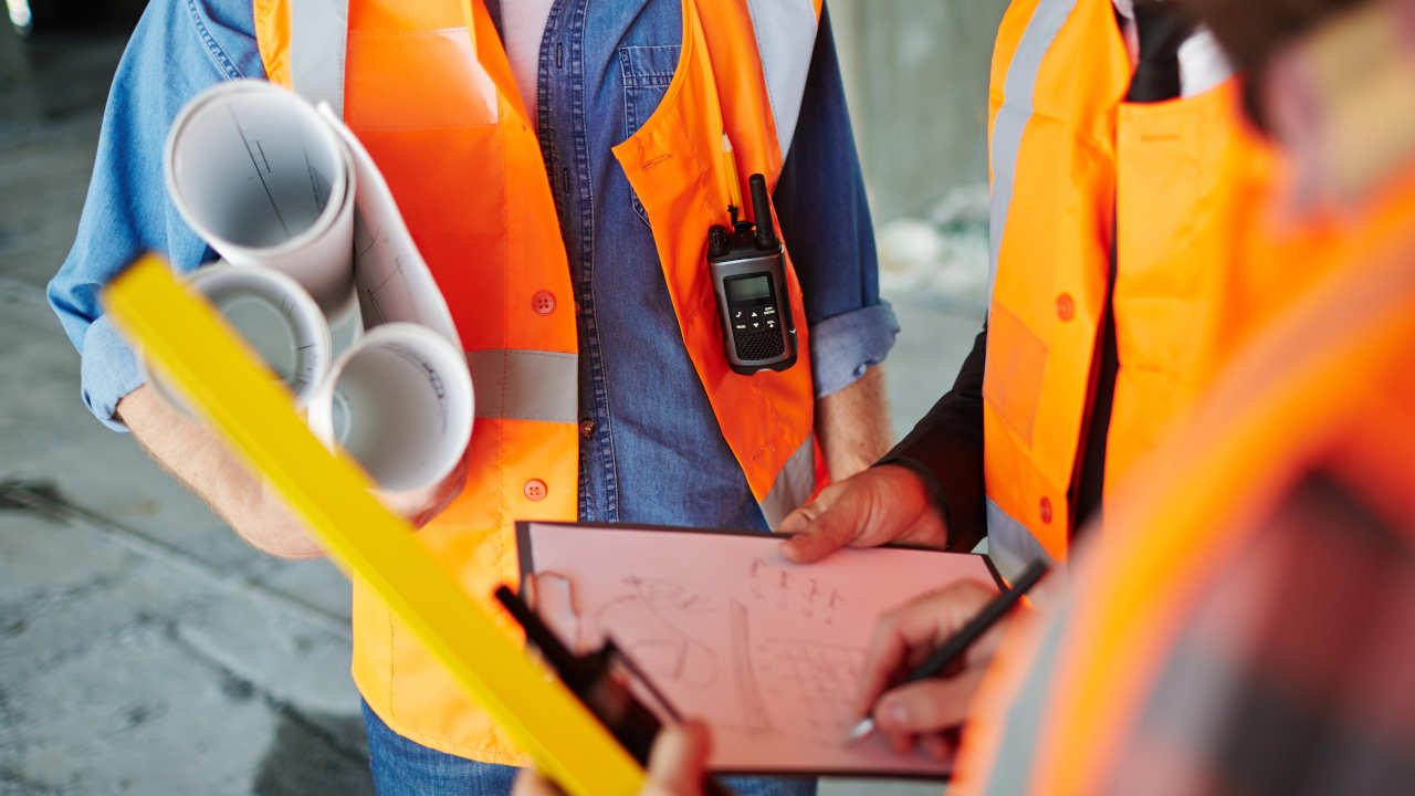 Grupo de trabalhadores analisando planos e documentos de construção.