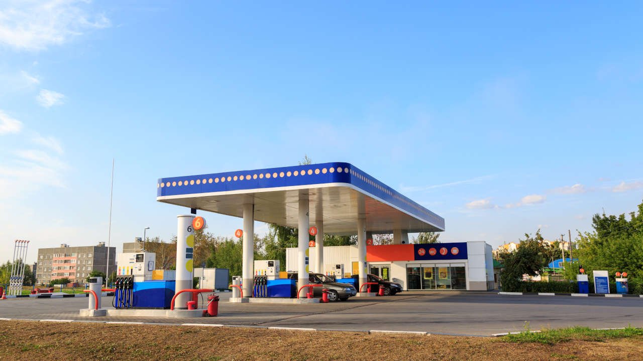 Posto de gasolina moderno com várias bombas de combustível e carros estacionados.