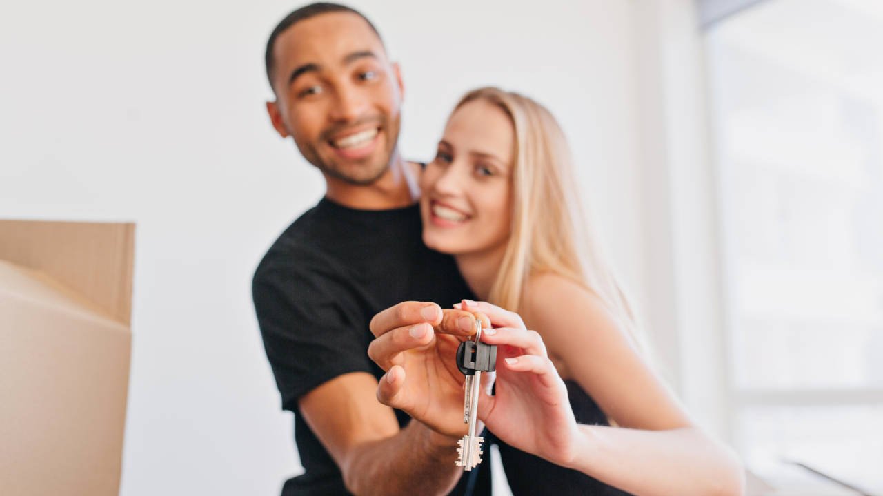 Casal sorridente segurando as chaves de sua nova casa.