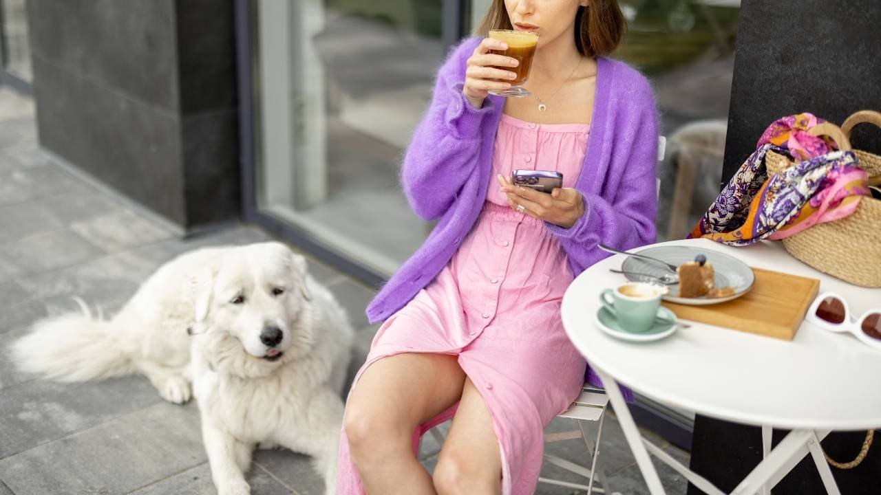 cliente desfrutando de café em uma cafeteria pet-friendly com seu cachorro ao lado.