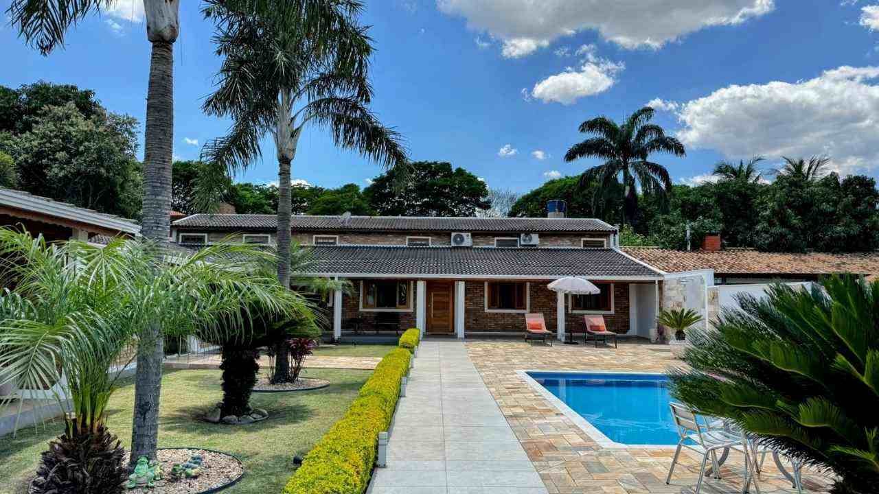 casa térrea com jardim amplo, piscina e área de lazer ao ar livre.
