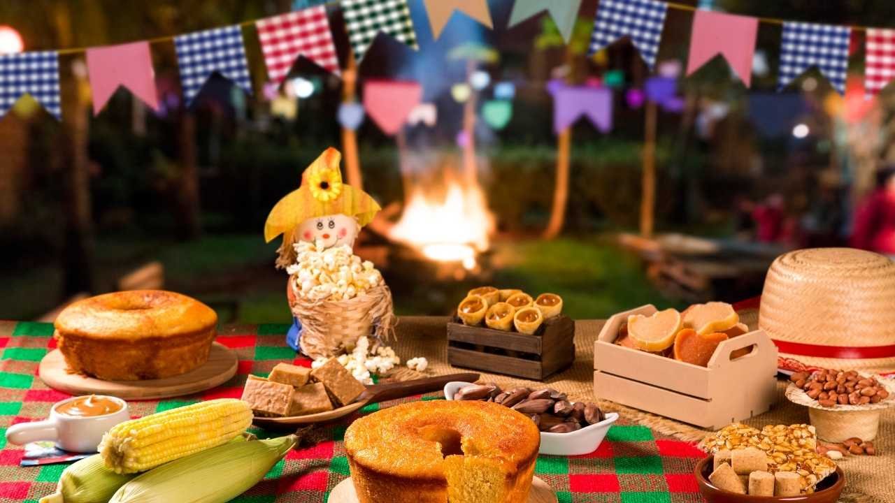 mesa com comidas típicas de festa junina e bandeirinhas coloridas.