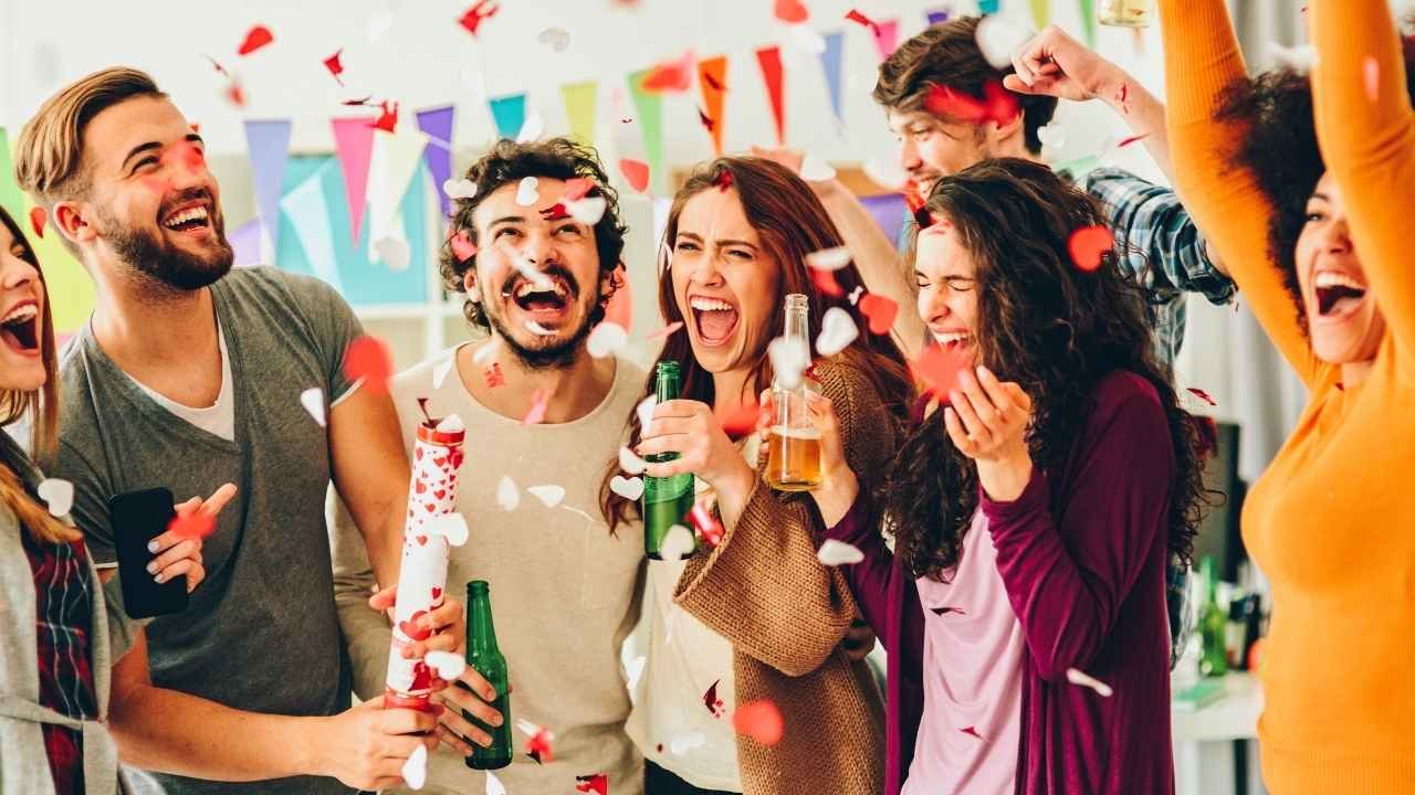 grupo de jovens comemorando animadamente em uma festa com música e confetes.