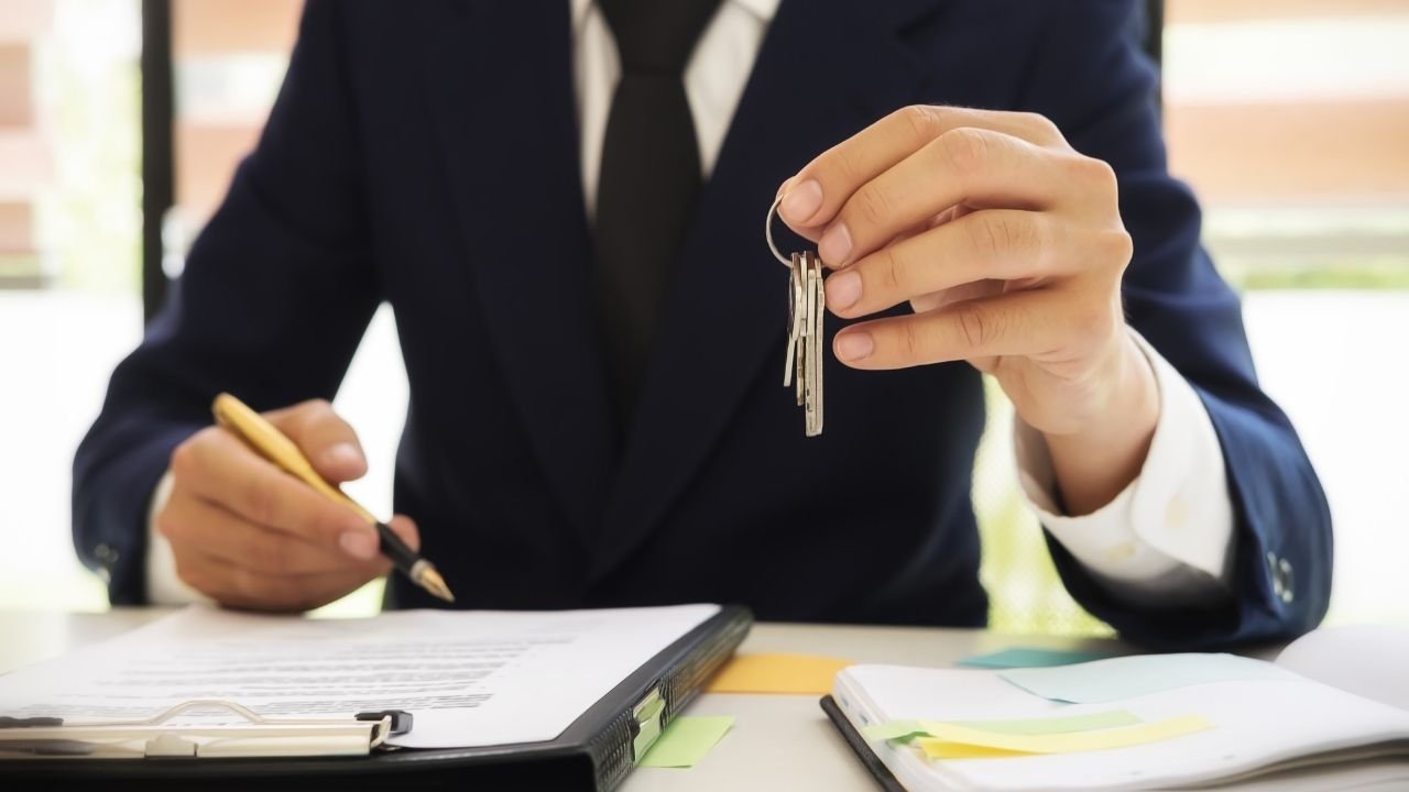 corretor segurando chaves durante assinatura de contrato de repasse imobiliário.
