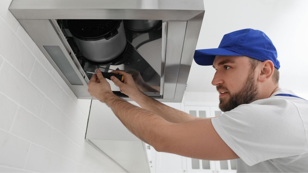 técnico realizando manutenção em coifa residencial.