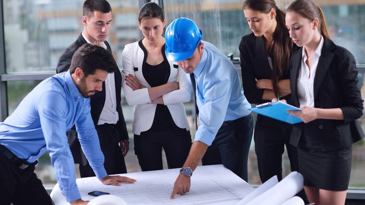 equipe analisando projeto de construção sobre uma mesa.