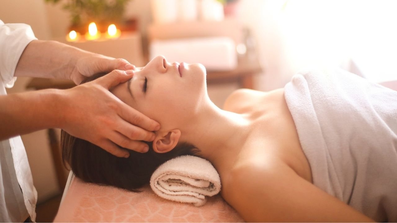 mulher recebendo massagem relaxante no rosto em ambiente aconchegante.