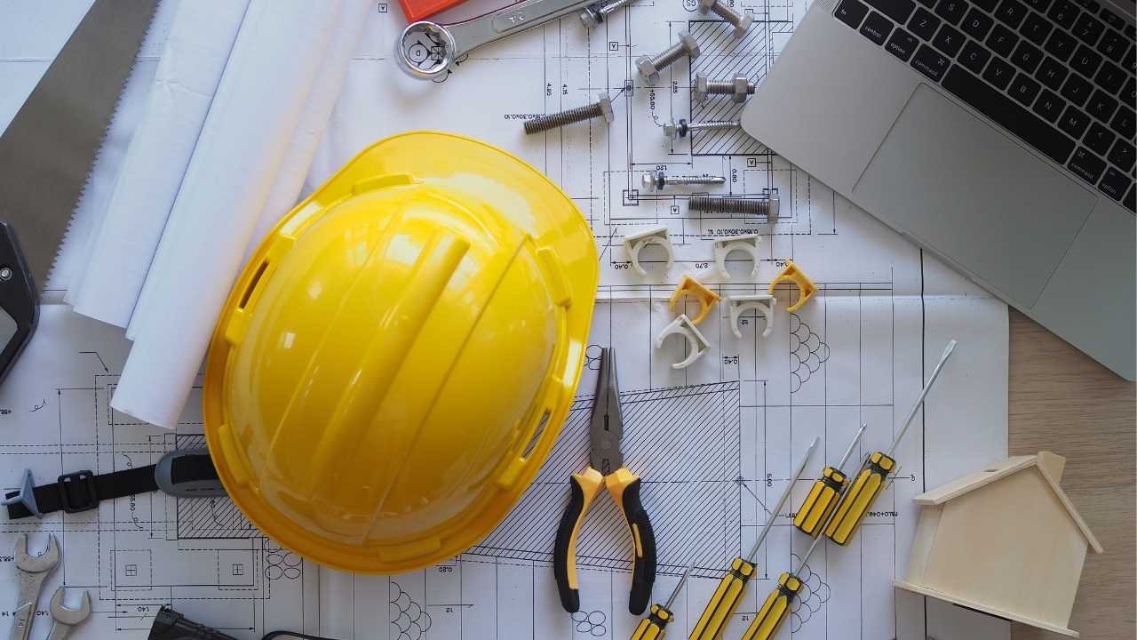 capacete e ferramentas sobre planta de projeto.