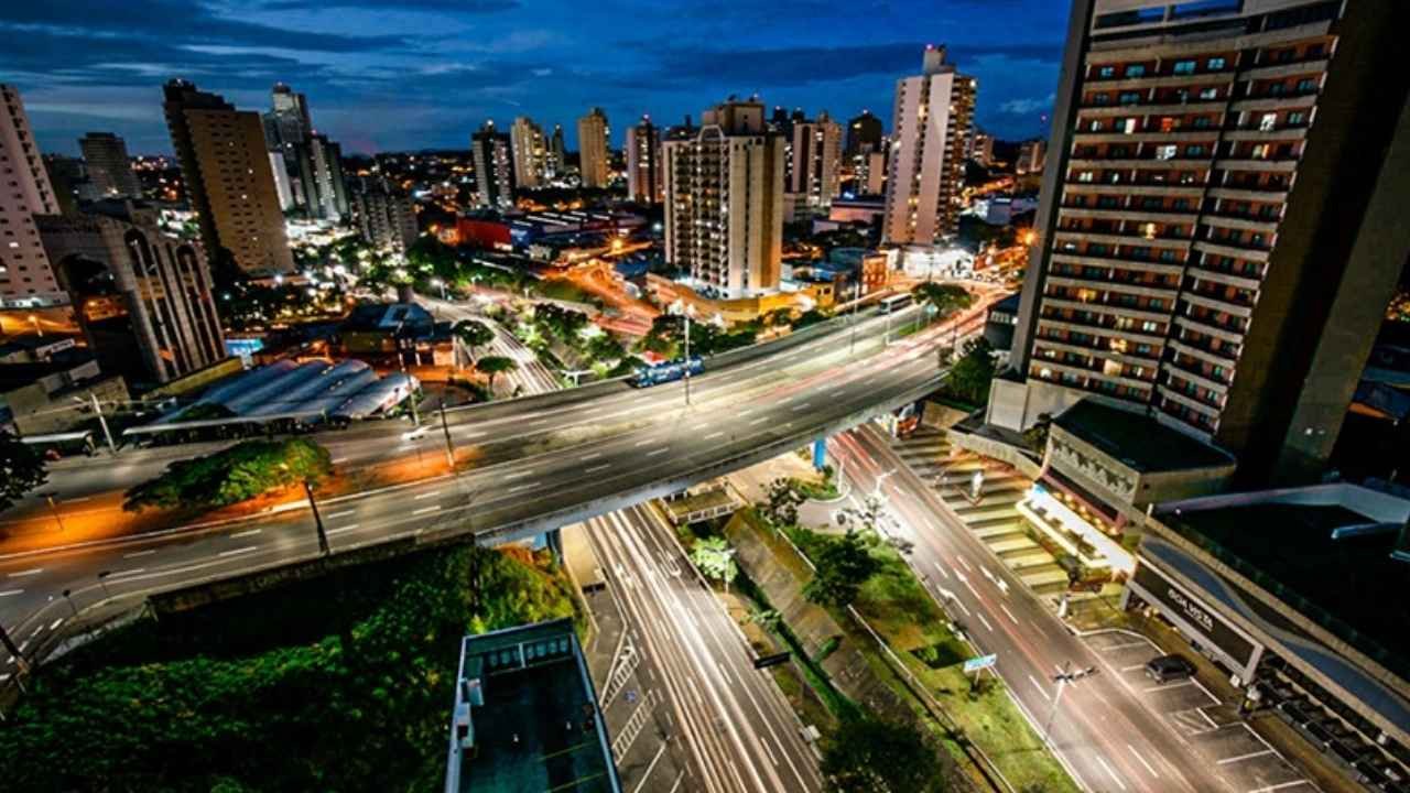 Paisagem noturna de Jundiaí com viadutos iluminados e prédios urbanos.