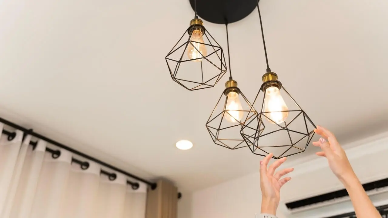 Exemplo moderno entre os tipos de luminária de teto, este conjunto de três pendentes possui estrutura aramada em formato de diamante preto. As lâmpadas de filamento aparentes trazem um estilo industrial e elegante para a decoração.